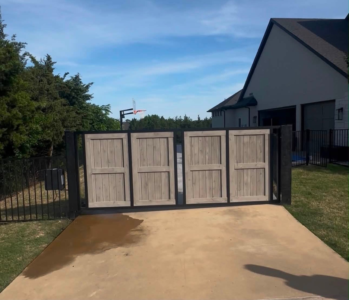 Modern gray wood double slide gate with a metal frame at a custom home