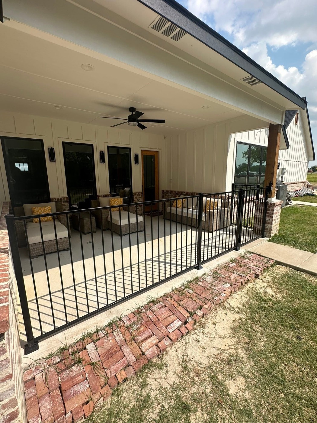 Black wrought iron fence around a covered back patio